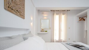 A hotel room with a bed, a bedside table with a magazine, a mirror, and a hanging towel rack.
