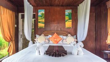 A wooden room with a bed, curtains, and two paintings on the wall.