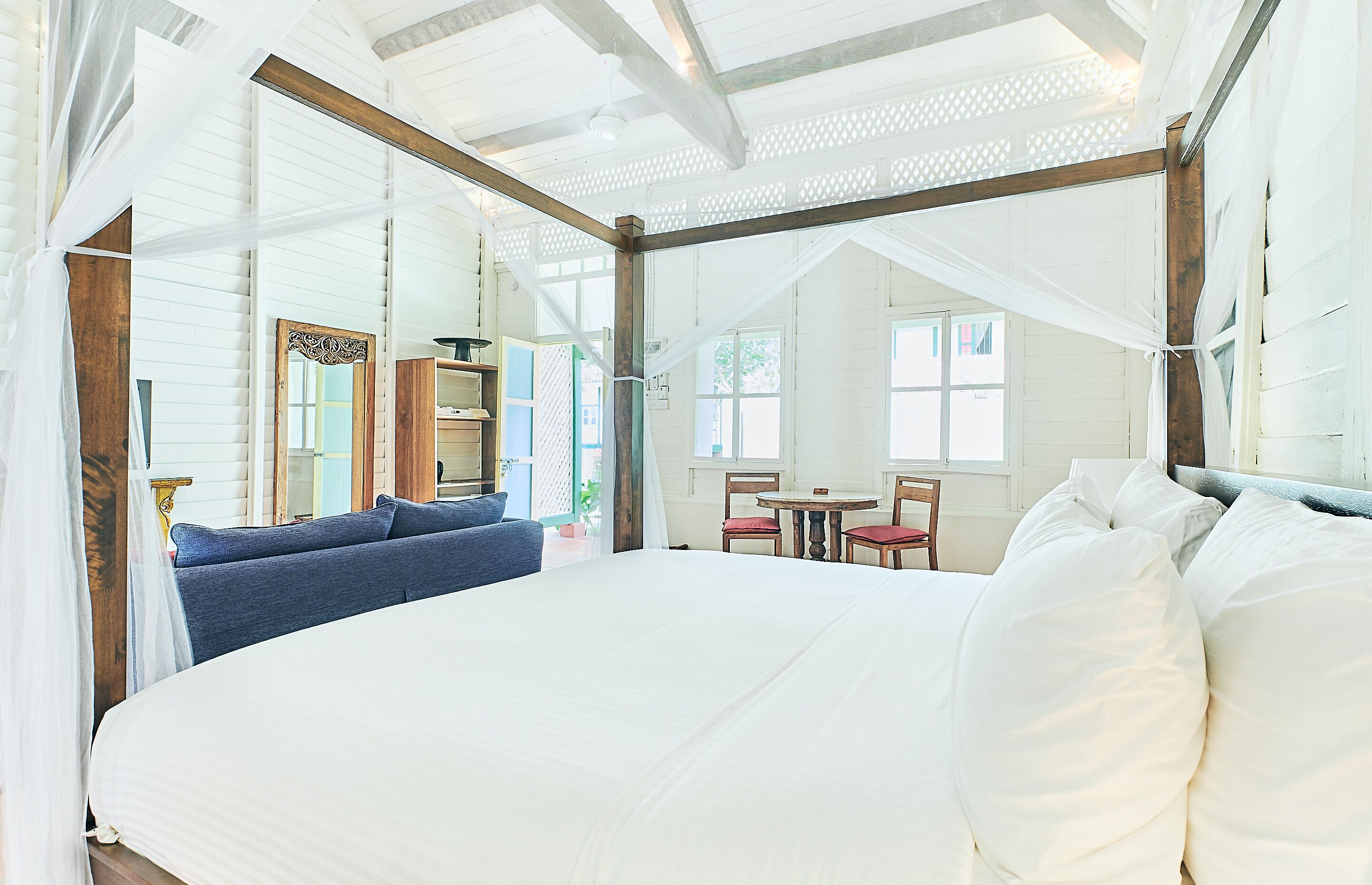 Quarto com uma cama grande, cabeceira de madeira, uma mesinha e uma cadeira.