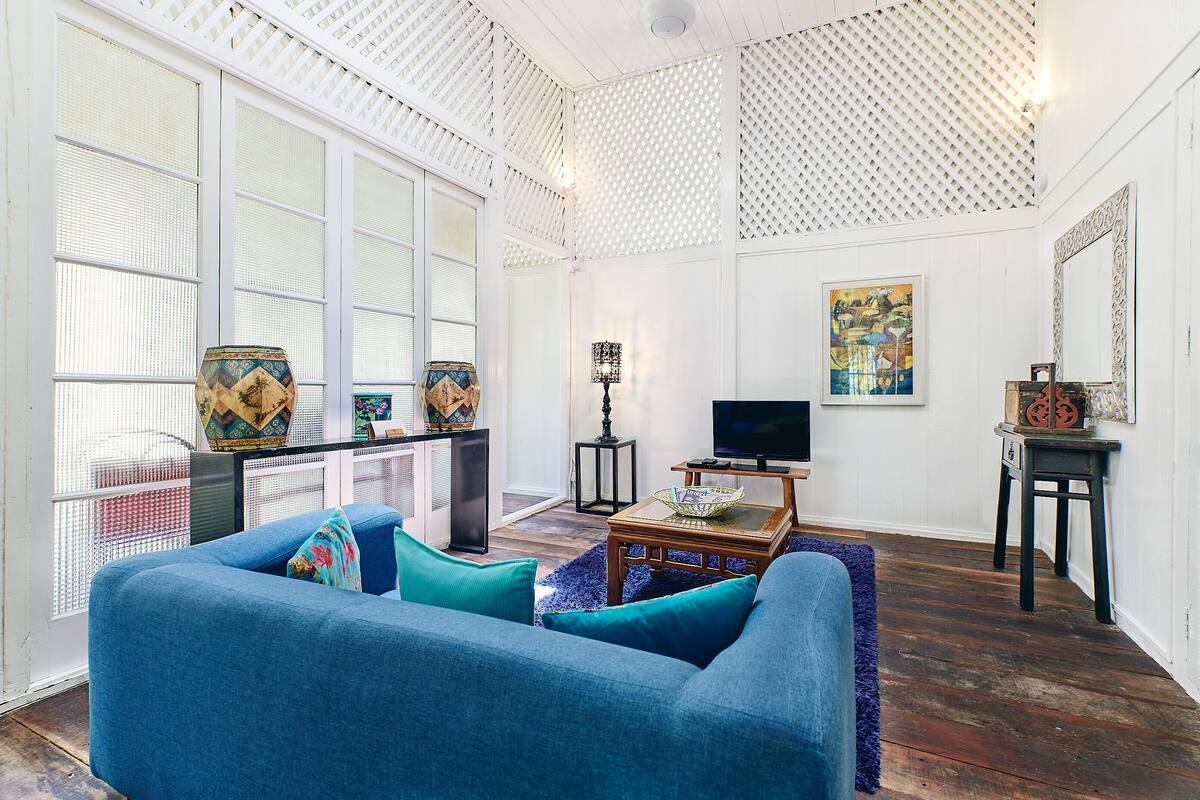 Una sala de estar con un sofá azul, televisor y objetos decorativos.