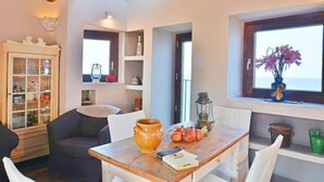 A cozy dining area with a wooden table, chairs, and a view of the sea through a window. - Terrazza Gabbiano Sopra (Cefalù)
