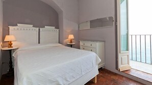 A bedroom with a bed, two bedside tables with lamps, a dresser, and a large window with a view. - Terrazza Gabbiano Sopra (Cefalù)