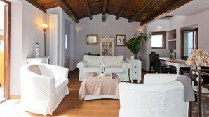 A cozy living room with a wooden ceiling, white furniture, and a dining area with a table and chairs. - Terrazza Gabbiano Sopra (Cefalù)