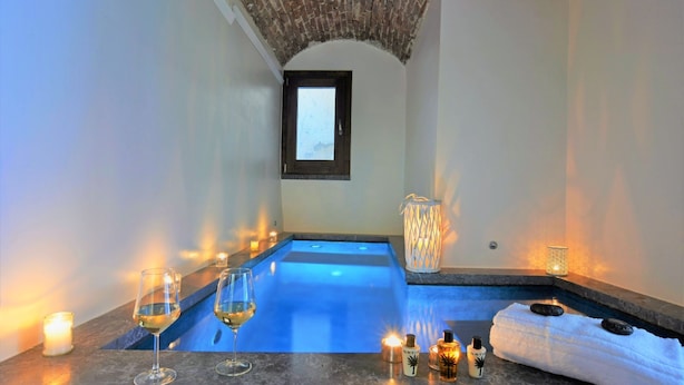 Zona de spa con piscina climatizada azul, velas y botellas de loción.