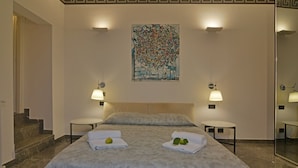 Una habitación de hotel con una cama, dos mesitas de noche, un espejo grande y un adorno en la pared.