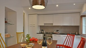 Una cocina moderna con armarios blancos, una mesa de comedor de madera y sillas rojas.