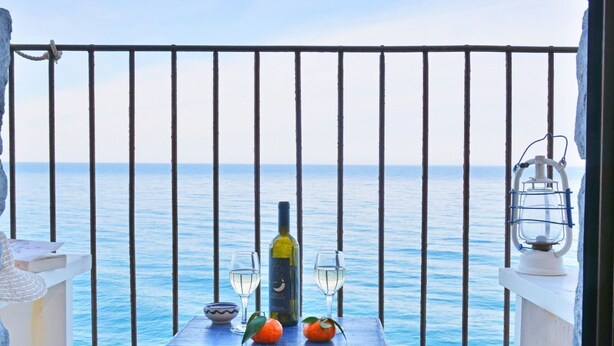 Ein Balkon mit Meerblick, eine Weinflasche, zwei Gläser und eine Laterne.