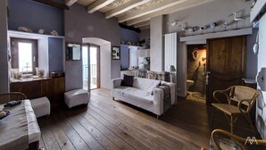 Ein geräumiger Wohnbereich mit Holzboden, einem weißen Sofa und einem Esstisch.