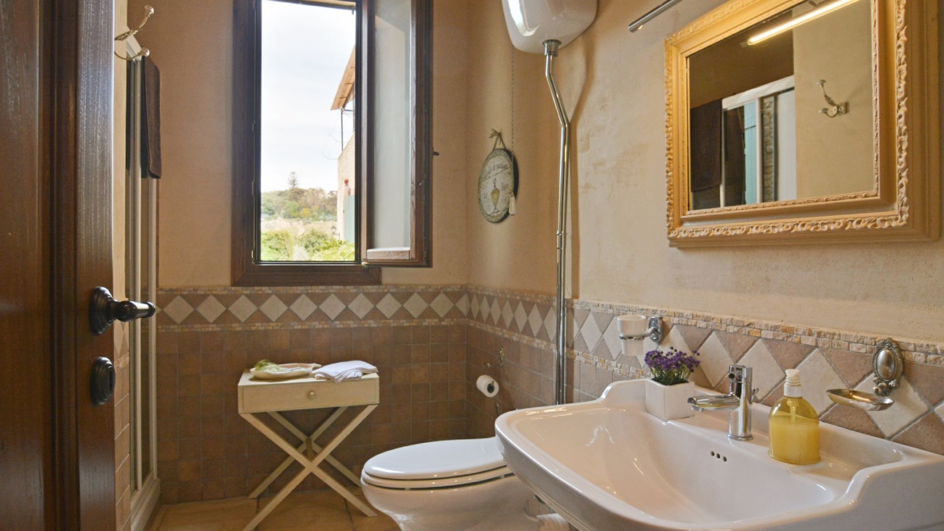 A bathroom with a toilet, sink, and window.