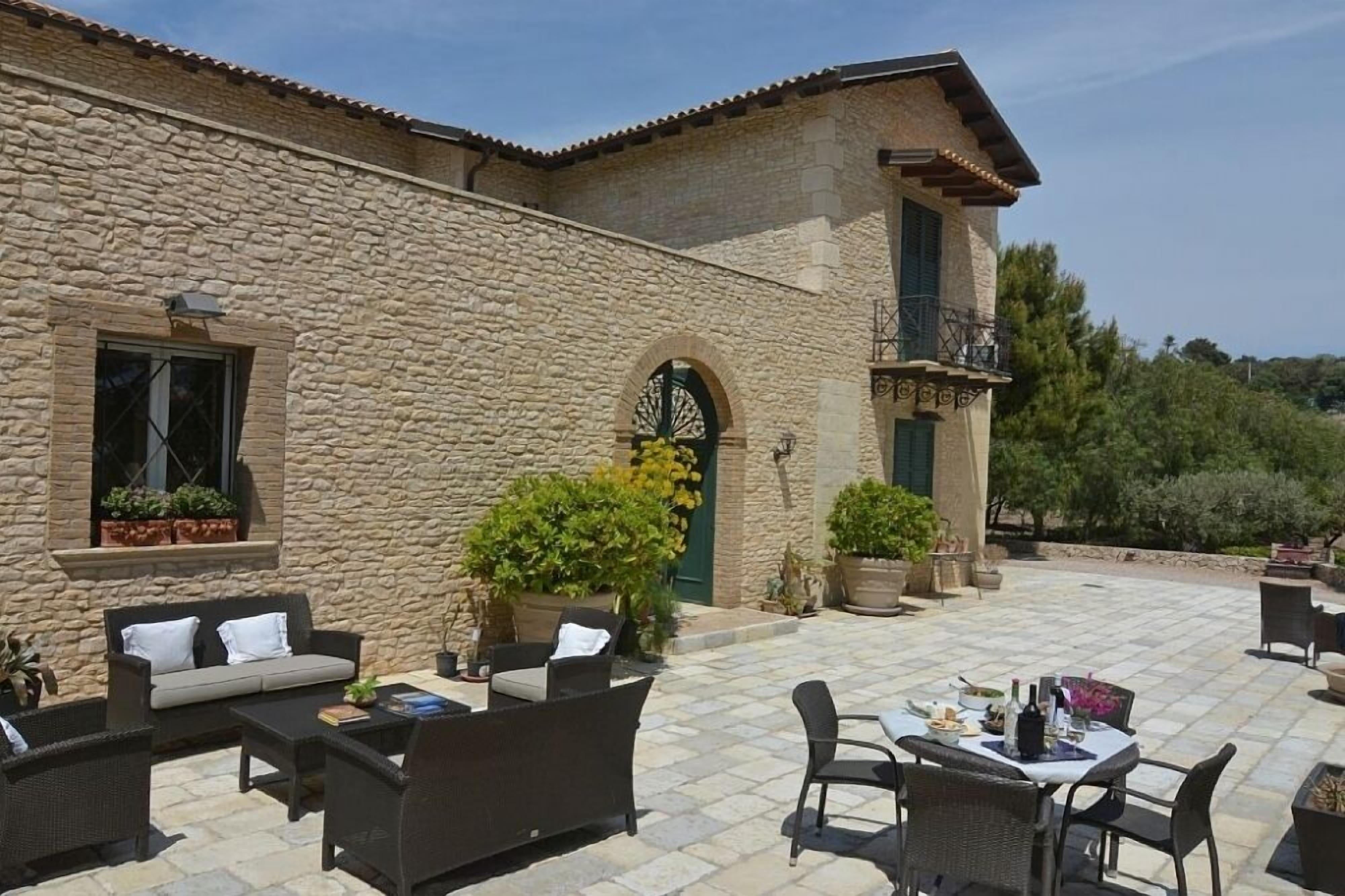A stone building with a patio area featuring outdoor furniture and potted plants.