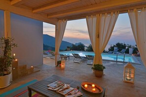 Un espacio al aire libre con piscina, sillas de descanso y velas.