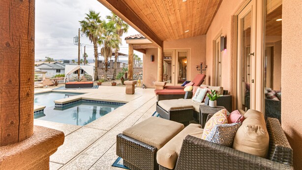 A covered outdoor area with a pool, wicker furniture, and a view of the surrounding landscape. - Private Pool, Spa, & Grills: Lake Havasu City Home (Lake Havasu City)