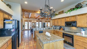 A spacious kitchen with granite countertops, wooden cabinets, a central island, a built-in oven, and a hanging chandelier. - Private Pool, Spa, & Grills: Lake Havasu City Home (Lake Havasu City)