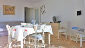A dining area with a round table covered with a white tablecloth, surrounded by white chairs.