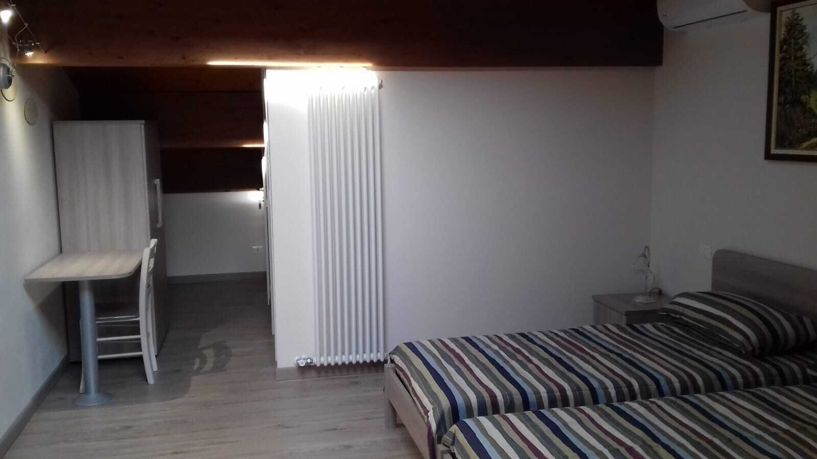 A bedroom with a bed, a chair, a radiator, and a small table.