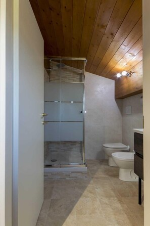 A small bathroom with a shower, toilet, and sink.