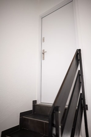 A staircase with a white door at the top, leading to an interior space.