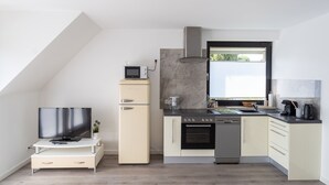 A modern kitchen with a built-in oven, microwave, and a small refrigerator. - Business Apartments Ost (Ratingen)