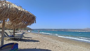 A beach with sun loungers and a thatched umbrella. - Studio for Couples -Traditional Stone built - Rural location (Kefalas nr Vamos) (Kefalas)
