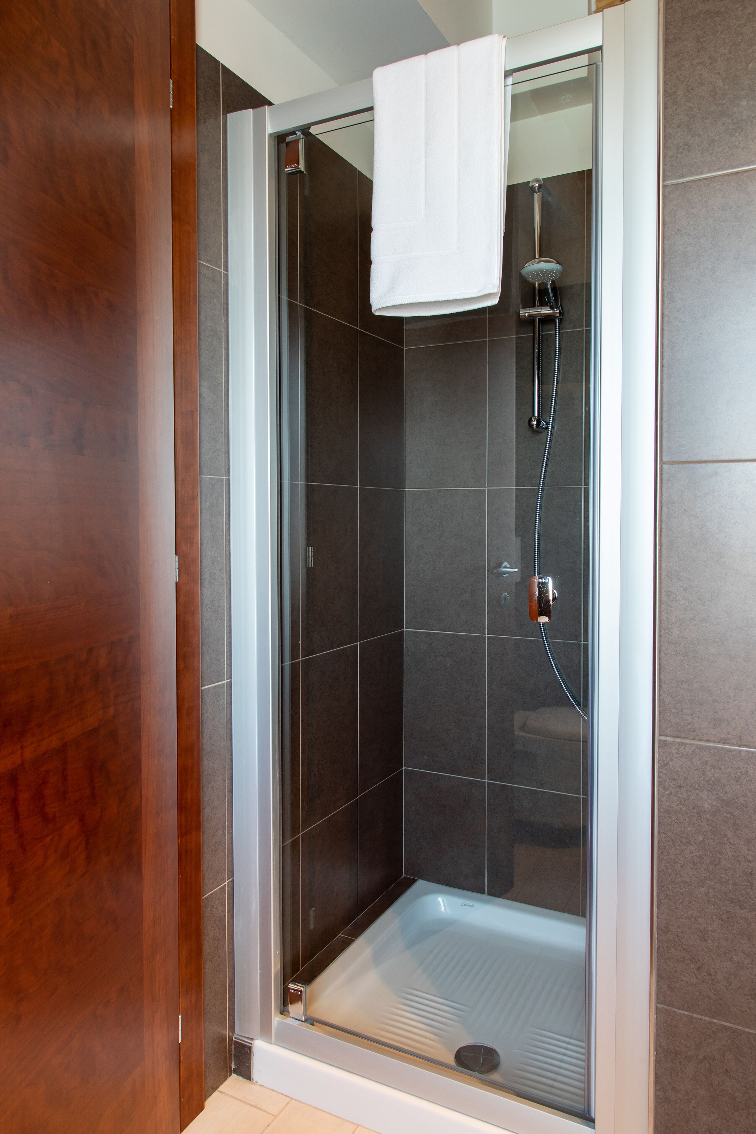 A glass-enclosed shower with a white towel hanging on the door.