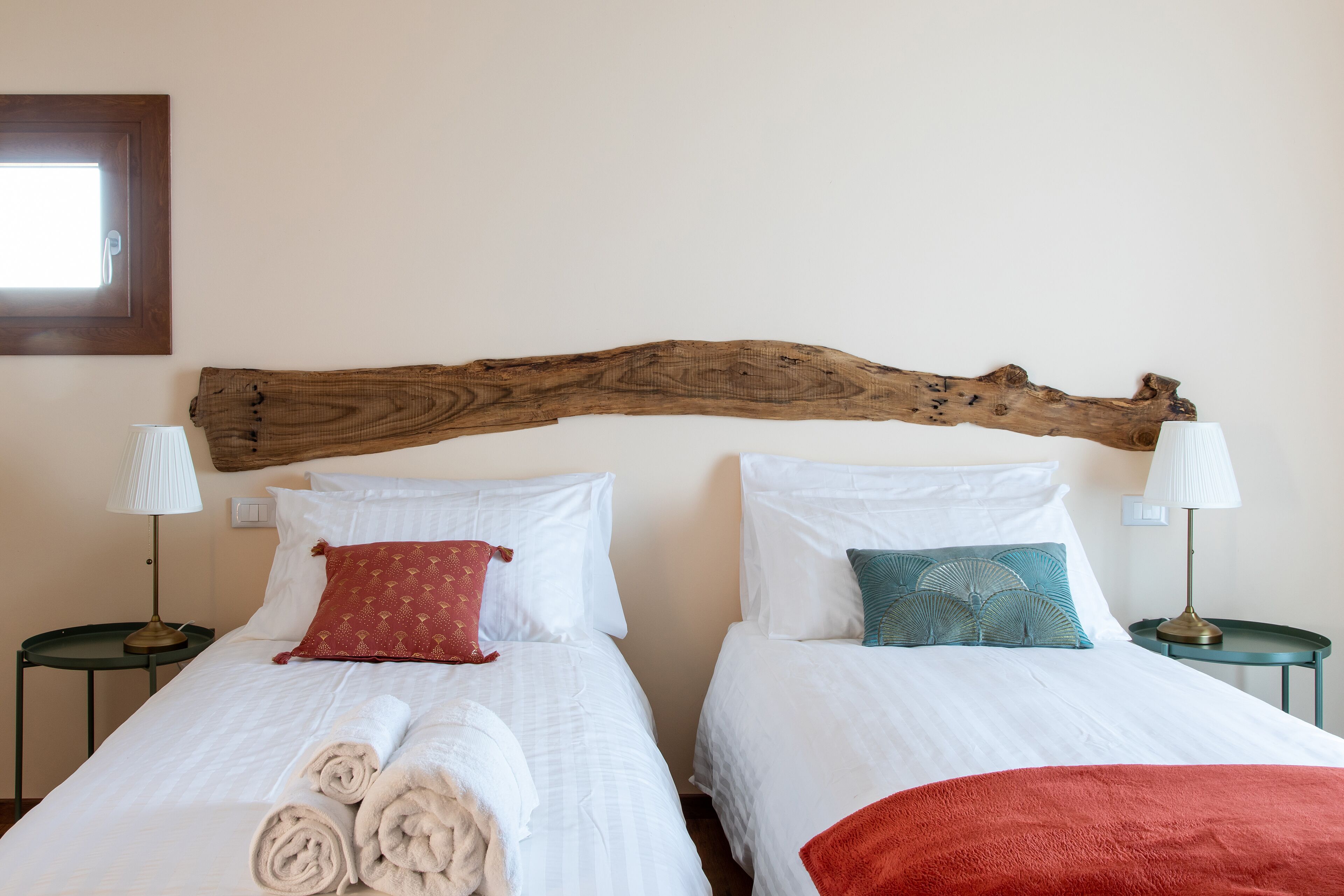 Two beds with white linens, a wooden headboard, and matching nightstands with lamps.