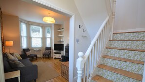 Un salon avec un canapé, un téléviseur et un escalier dont les marches sont décorées de motifs.