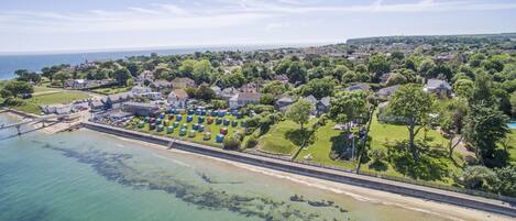Vista aérea de uma vila costeira com praia, casas e um grande número de cabanas coloridas.