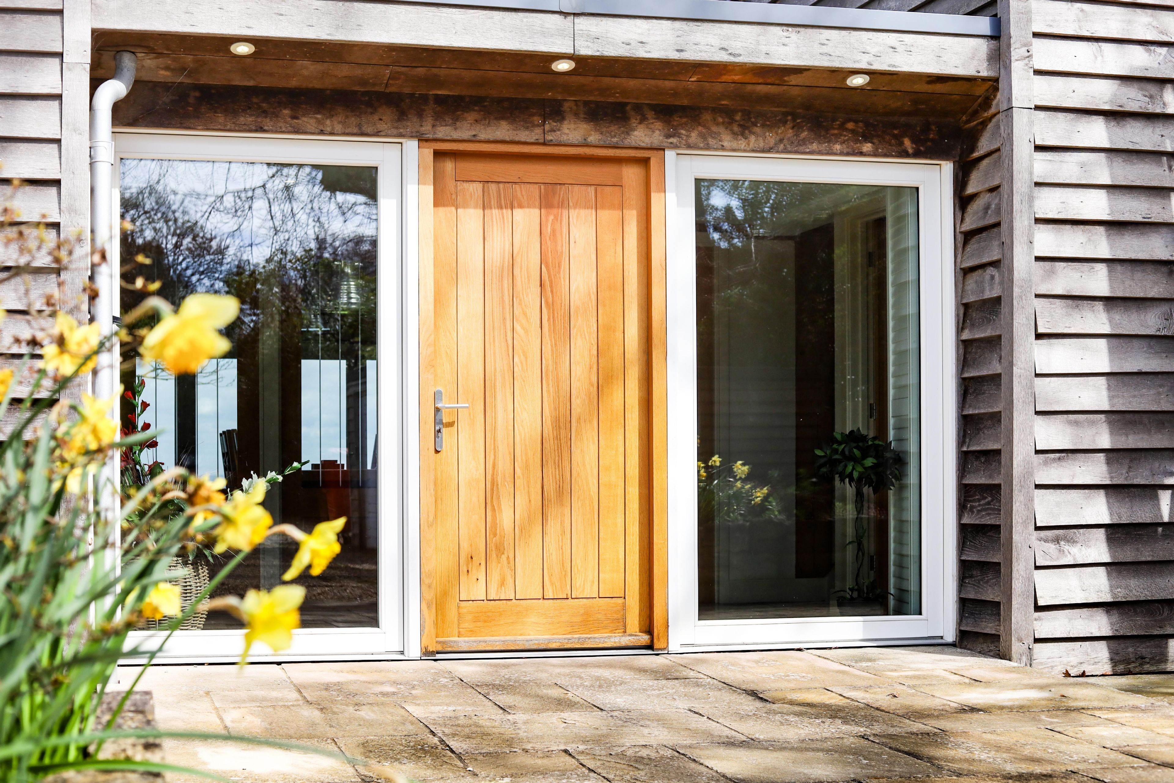 A wooden door with a glass panel, a stone-paved entrance, and a wooden exterior wall.