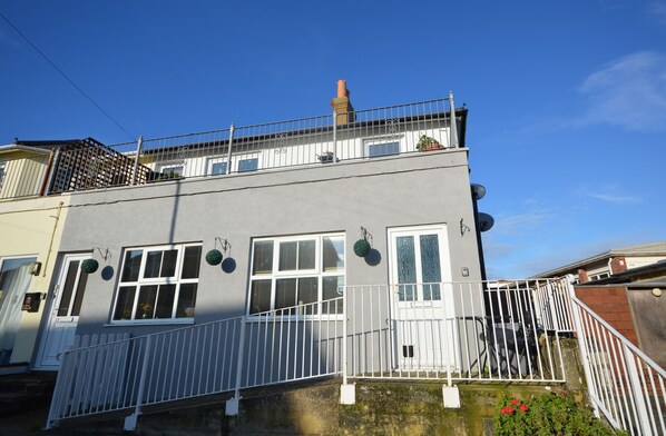 A two-story building with a balcony, white railings, and a chimney. - Beachfield (Sandown)