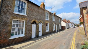 A row of traditional brick houses with white-framed windows and doors, a clear sky, and a quiet street. - Admirals Cottage (Yarmouth)