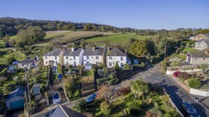A residential area with houses, a road, and a hilly landscape in the background. - Charnwood Cottage (Sandown)