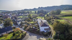 An aerial view of a rural village with houses, roads, and green fields. - Charnwood Cottage (Sandown)