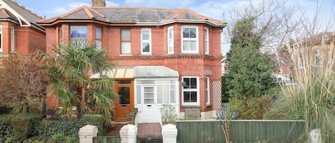 A red brick house with a bay window, a front door, and a small porch.