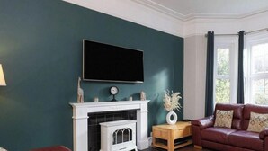 Una sala de estar con chimenea, un sofá de cuero y un televisor en la pared.