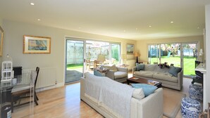 A spacious living room with a large window, a dining area, and a cozy seating arrangement. - Hope Cottage (Bembridge)