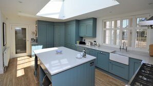 A modern kitchen with teal cabinetry, a central island, and a skylight. - Hope Cottage (Bembridge)