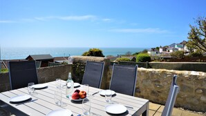A table set for dining with a view of the sea and houses in the background. - Pebble Cottage (Ventnor)