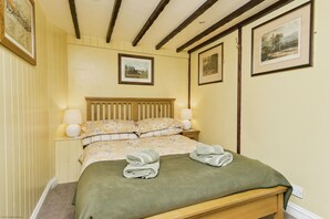 Un dormitorio con una cama de madera, ropa de cama floral y dos cuadros en la pared.