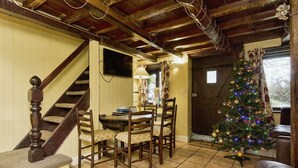 Un coin repas avec un escalier en bois, un sapin de Noël et une table entourée de chaises.