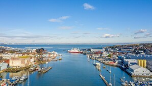 A harbor with boats, a large ship, and industrial buildings. - Harbour View (East Cowes)