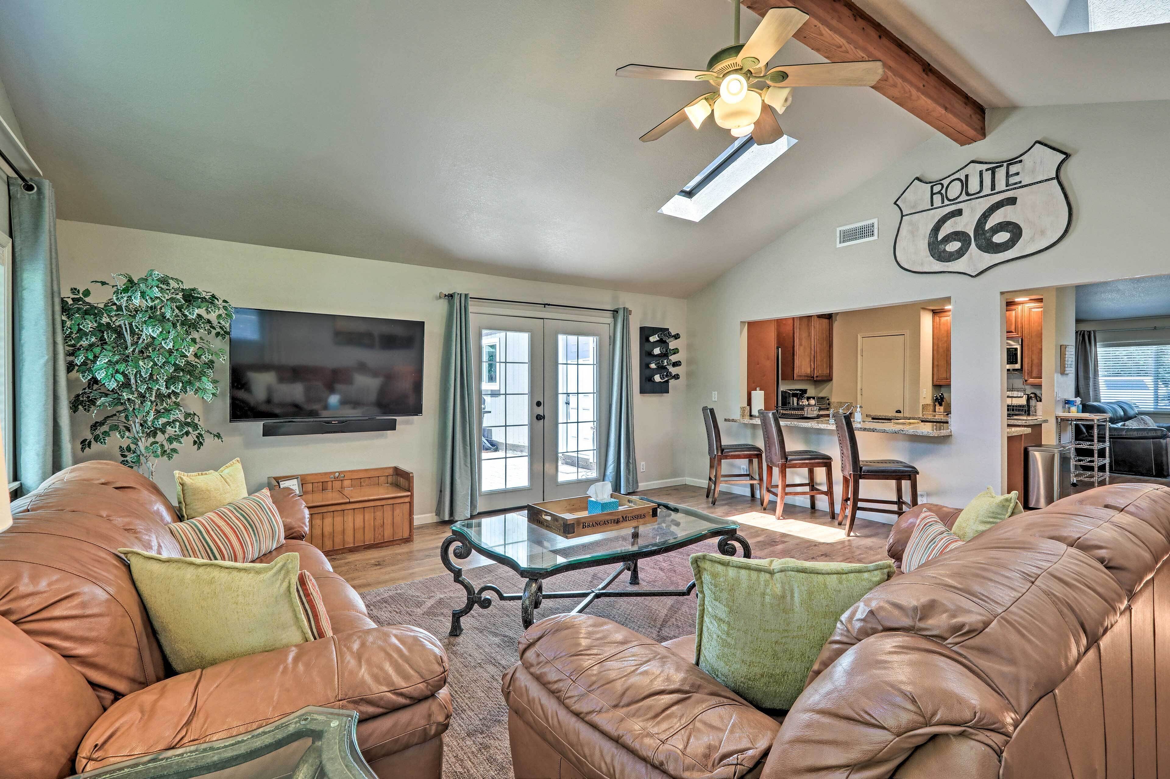 A living room with leather sofas, a glass coffee table, and a ceiling fan. A sign reading "ROUTE 66" is on the wall.