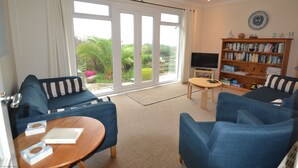 A living room with a blue sofa, a coffee table, a bookshelf, and a TV.