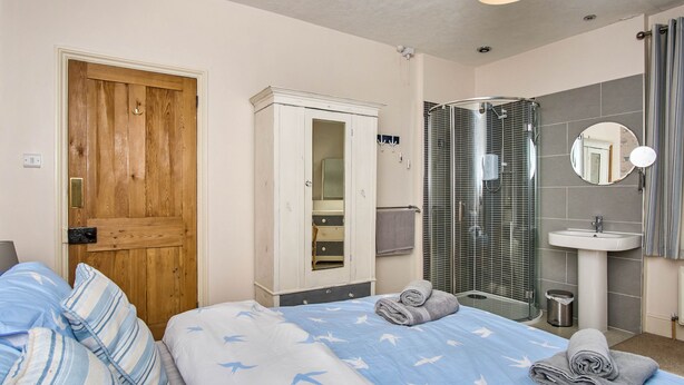 Un dormitorio con puerta de madera, armario, zona de ducha y cama con toallas.