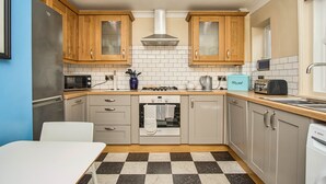 Cocina compacta con armarios de madera, horno Bosch, microondas y tostadora.