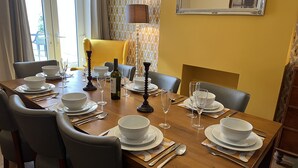 Un comedor con una mesa de madera dispuesta para cuatro personas, incluyendo cuencos, platos y cubiertos blancos.