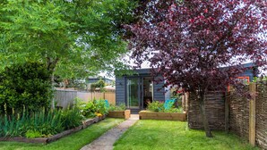 A modern house with a garden, a pathway, and a wooden fence.