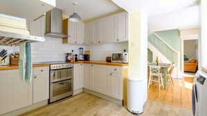 A modern kitchen with white cabinets, a stainless steel range, and a wooden countertop.