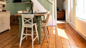 A dining area with a wooden table, chairs, and a staircase leading to another room.