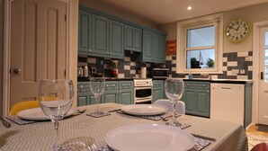 Uma sala de jantar com uma mesa posta para quatro pessoas, incluindo copos de vinho e pratos.