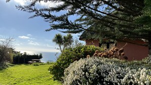 A well-maintained garden with a lawn, a variety of shrubs, and a view of the sea. - Mole Cottage (Shanklin)